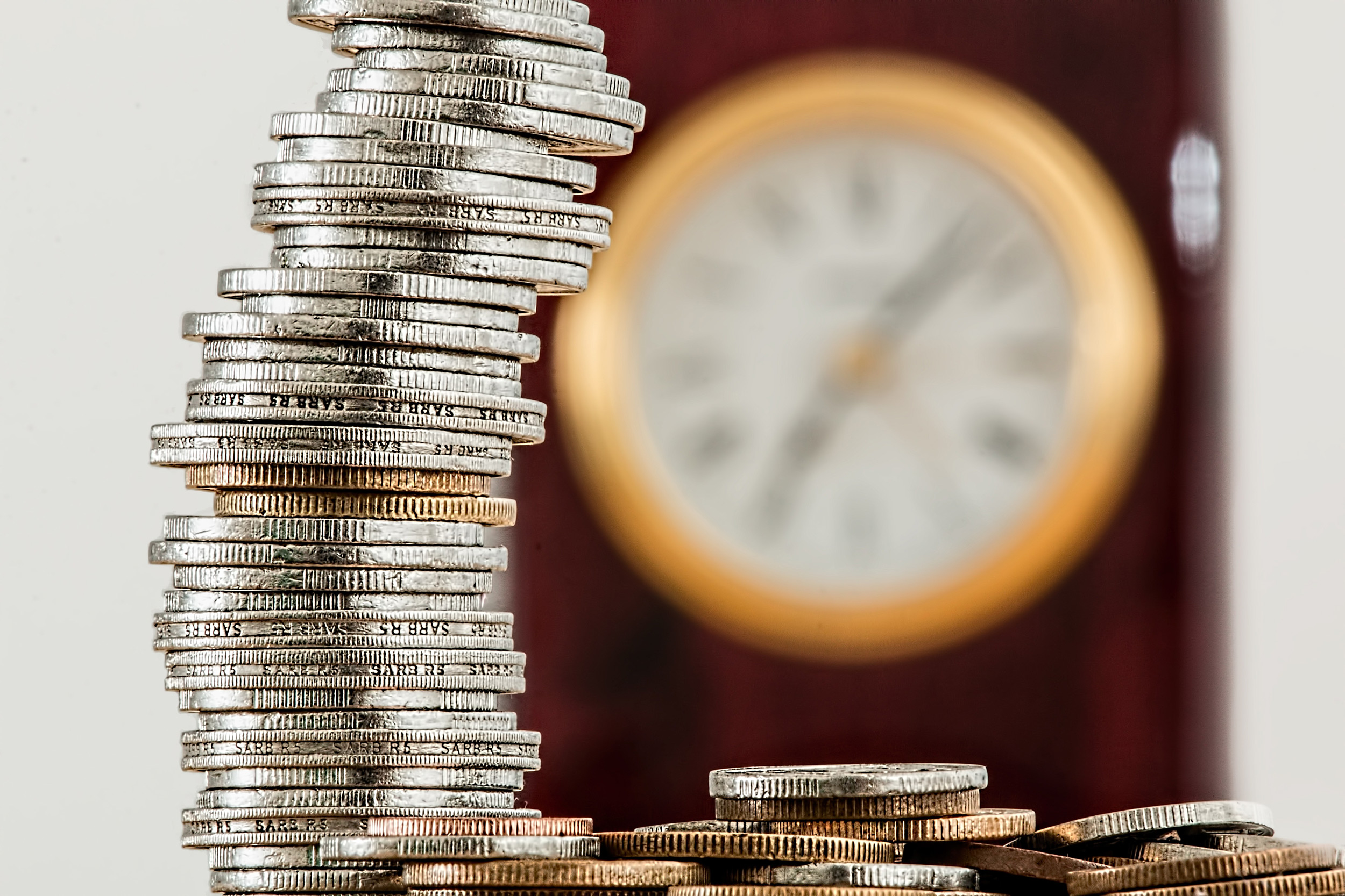 coins stacked in front of clock